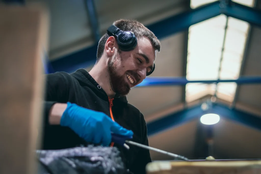 Medewerker met handschoenen en gehoorbescherming aan het werk
