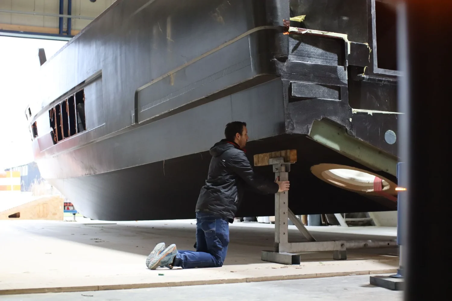 Medewerker knielt bij de onderzijde van een bootcasco