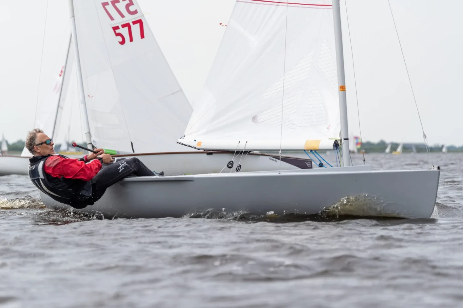 Kleine zeilboot varend tussen andere zeilers