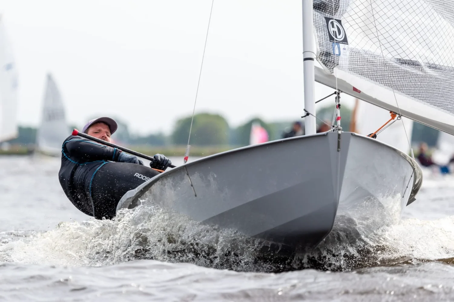 Zeiler hangt buitenboord in een kleine wedstrijdboot