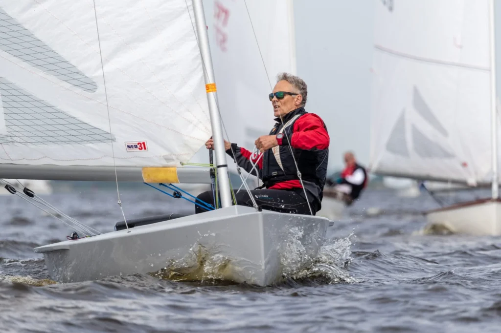 Zeiler in een kleine grijze wedstrijdboot