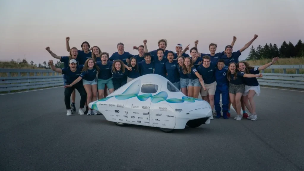 Team poseert met een witte zonneauto
