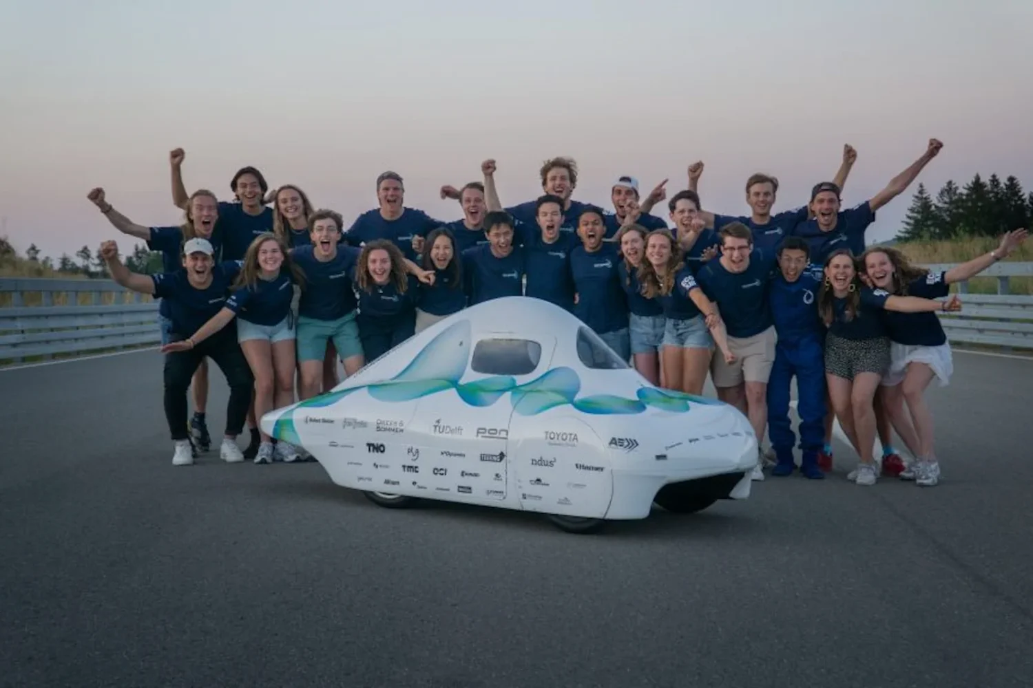Team poseert met een witte zonneauto