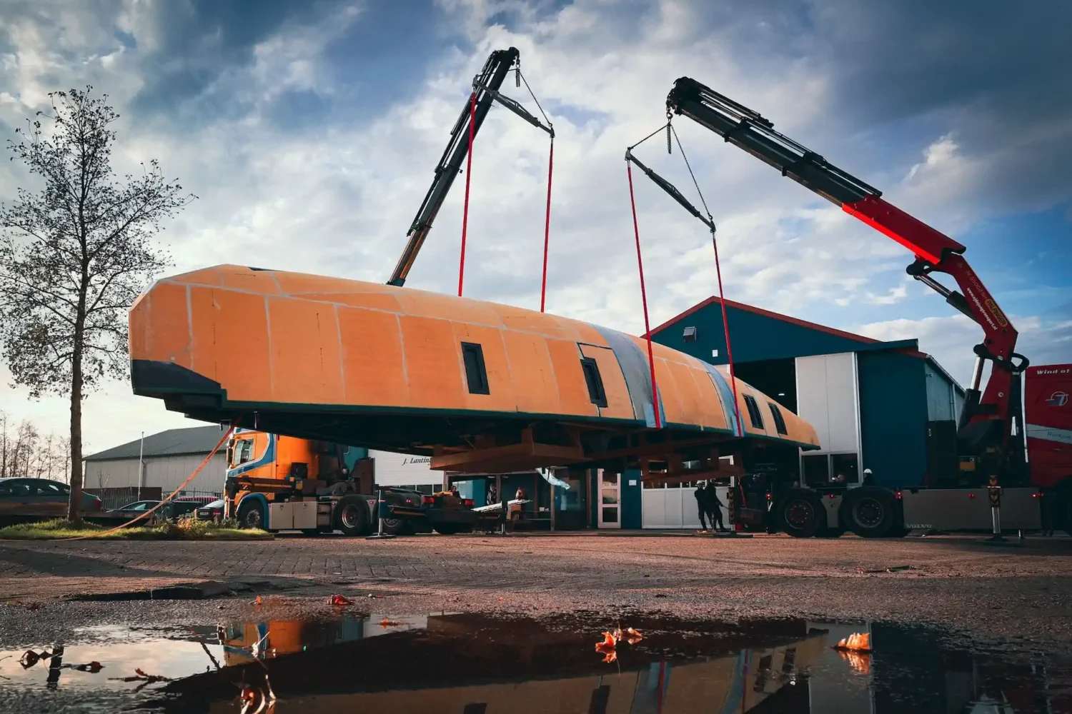 Oranje bootcasco wordt met twee kranen gehesen