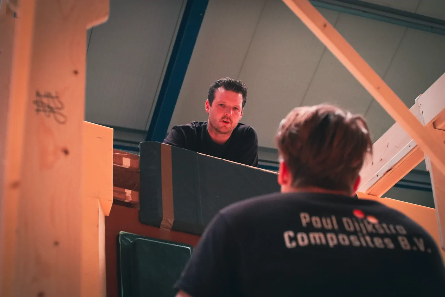 Medewerkers overleggen bij een houten bouwframe