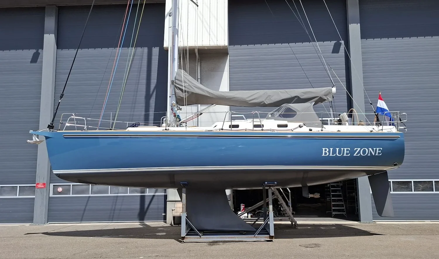 Blauw zeiljacht Blue Zone op steunen voor een loods