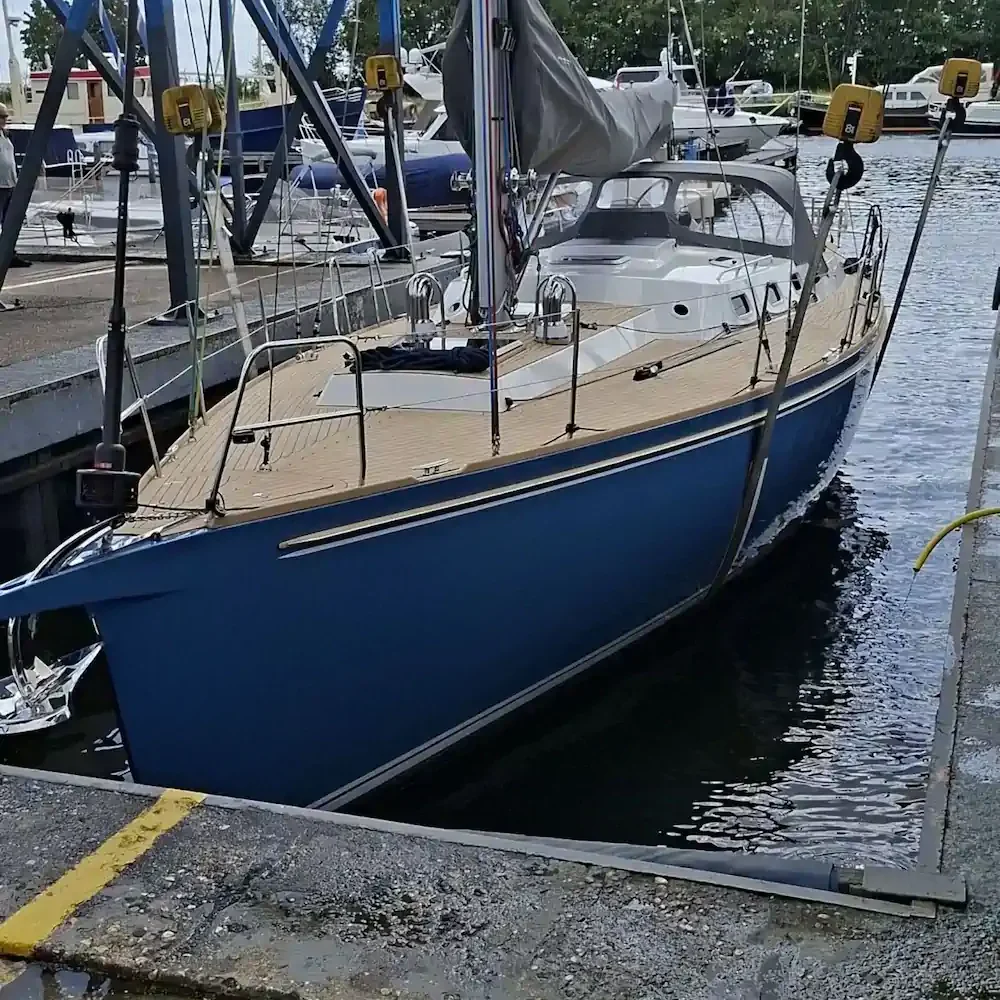 Blauw zeiljacht langs een steiger