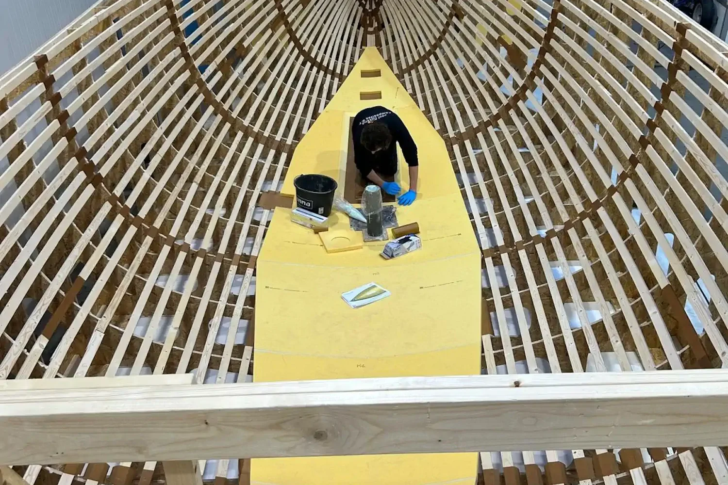 Houten spantenframe voor een bootromp met een geel middendeel